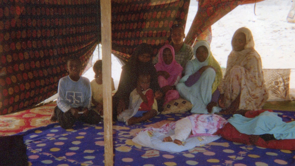 A family of freed slaves sit on the floor of a tent as they share their story